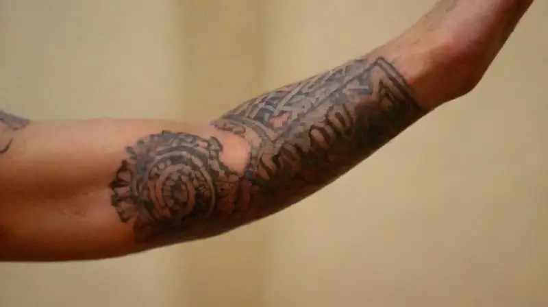 Tatuajes culturales detallados en brazos musculosos