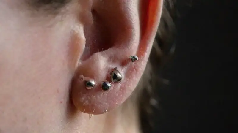 Oreja con piercings abstractos y detallados