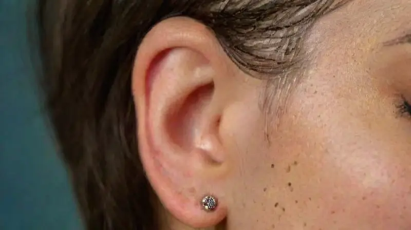 Oído con piercings y tattoo detallado