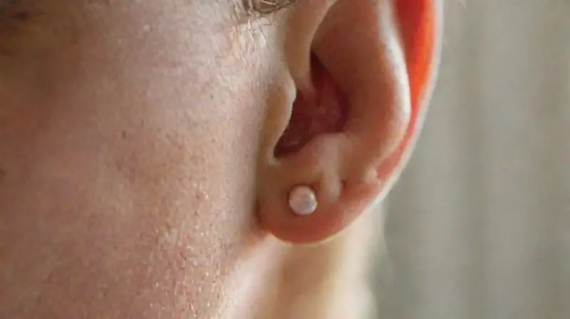 Primer plano de oreja con piercing temporal brillante