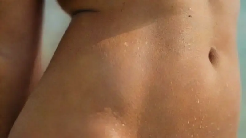 Abdomen bronceado con piercings y verano